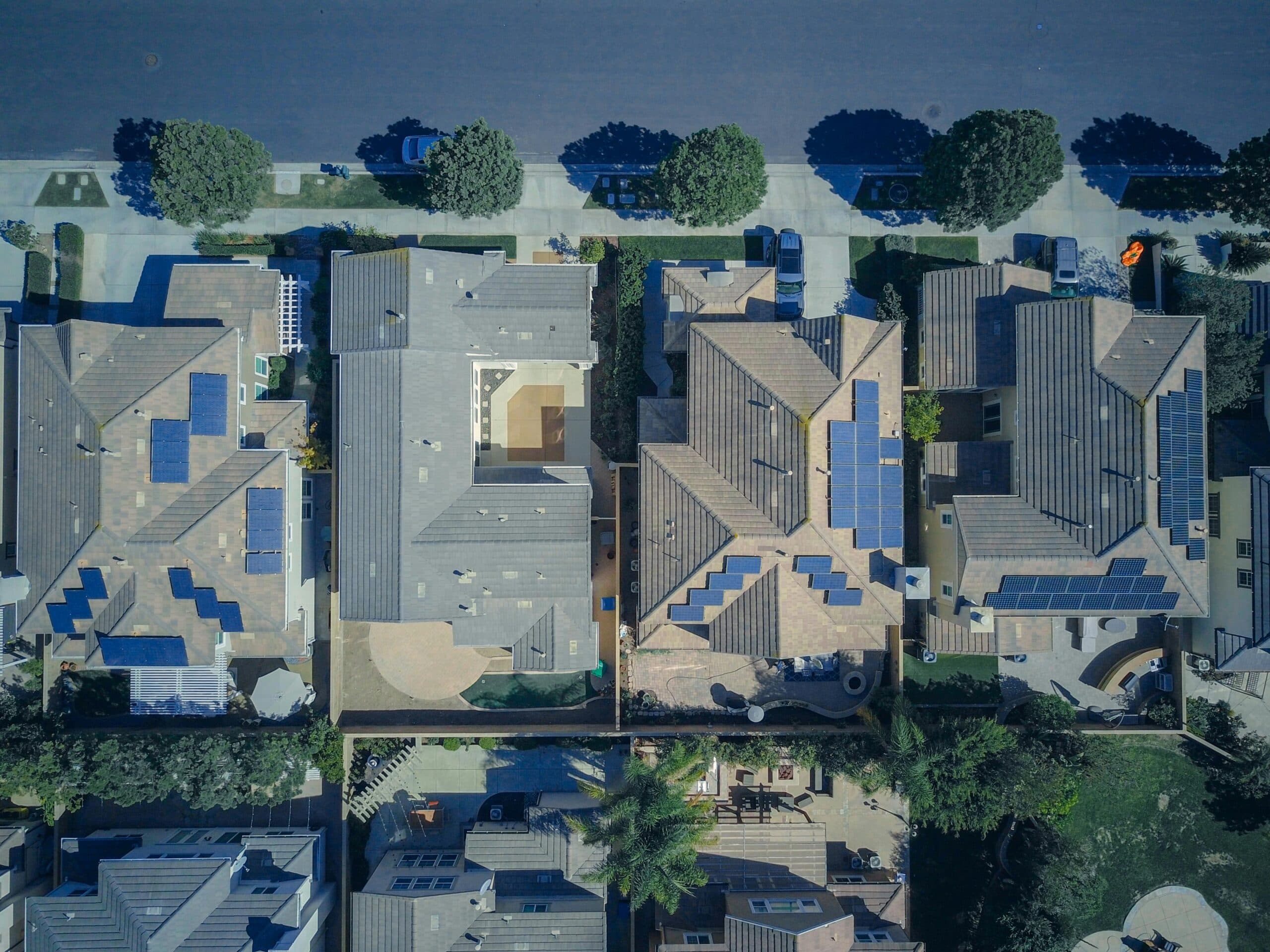 Aerial view of neighborhood with solar panels installed on multiple rooftops