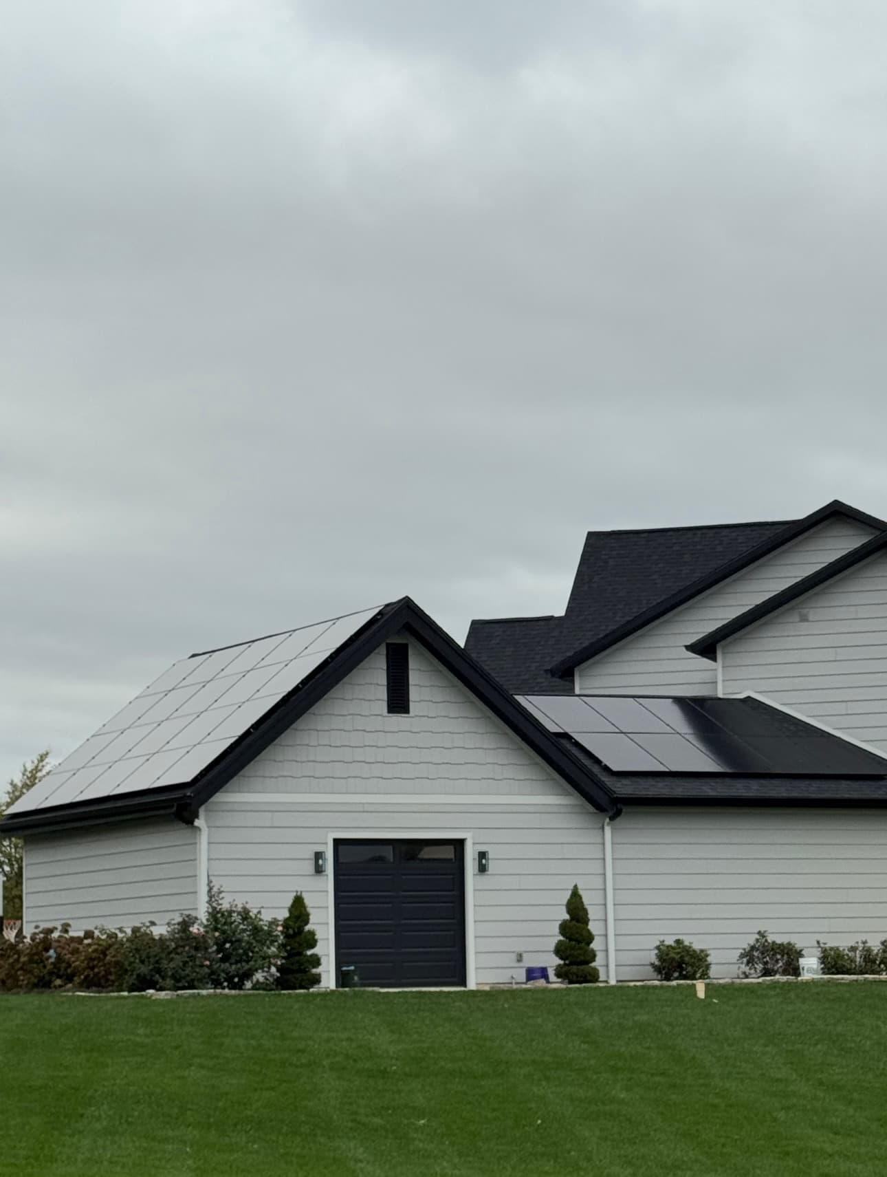 Solar panels installed on a modern white farmhouse with multi-section roof